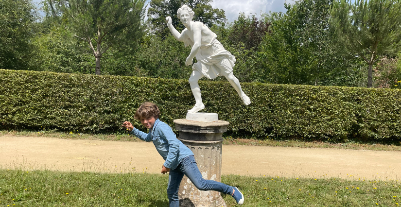 Enfant imitant une statue dans un lieu de patrimoine 